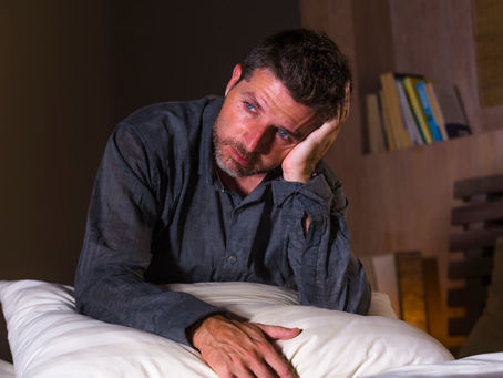 Man in bed with pillow looking exhausted, flat, numb