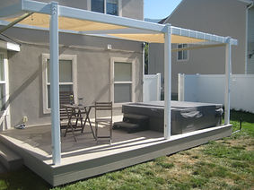 A modest backyard deck with a covered awning and a hot tub jacuzzi