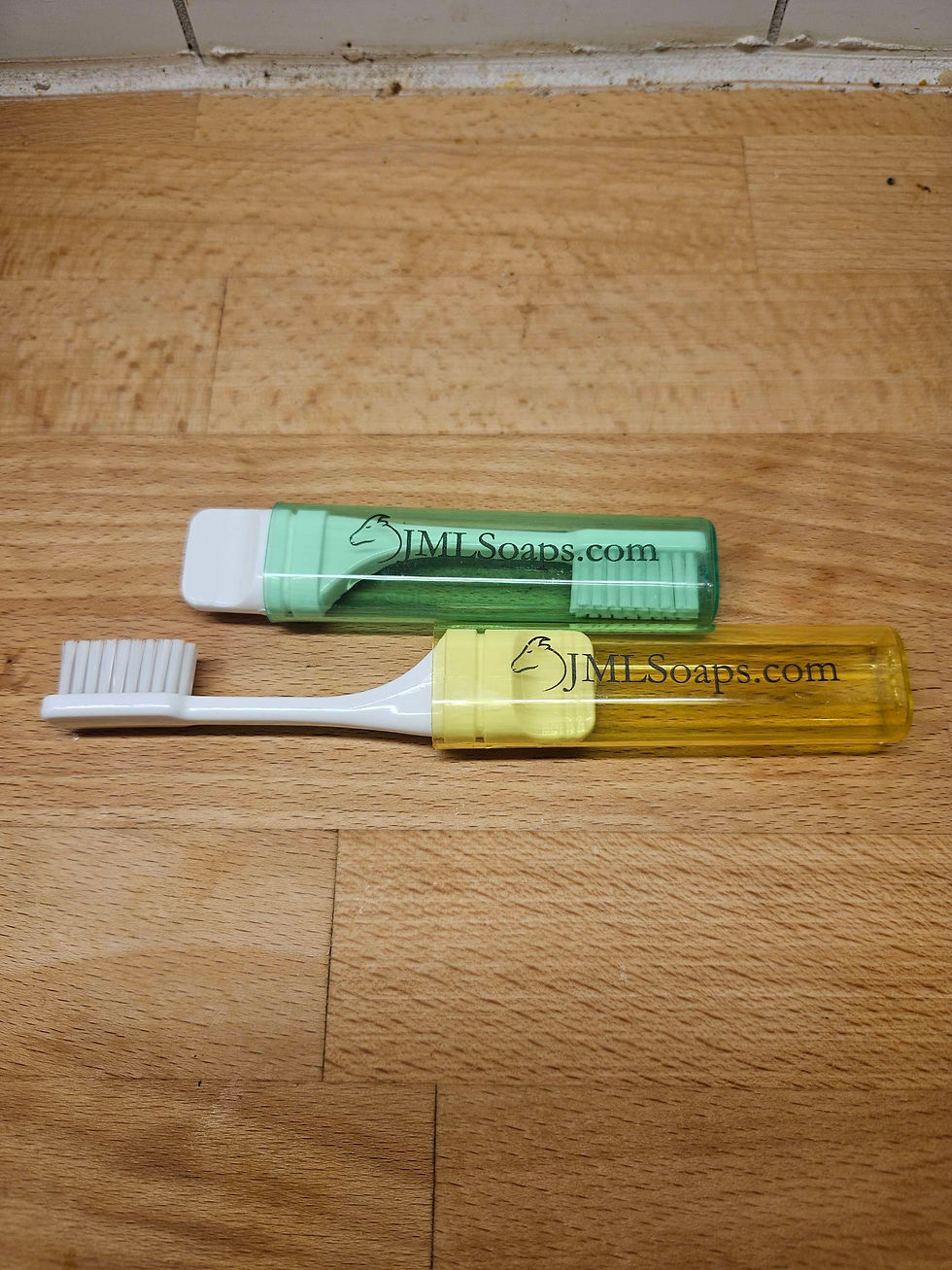 Thumbnail: Two toothbrushes in cases on wood, one green and one yellow.