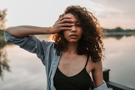 Portrait of a woman in front of a body of water, feeling the mind and body effects of trauma