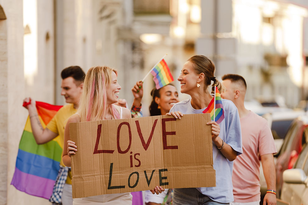 Lesbian women and LGBTQ allies walking in PRIDE Parade with sign that reads "Love is love."