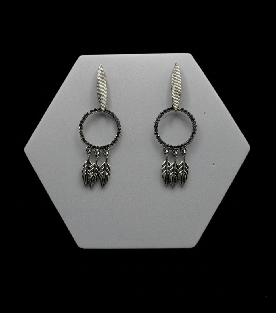 Silver earrings on display, featuring a circular design and dangling leaves Lavish Jewellery