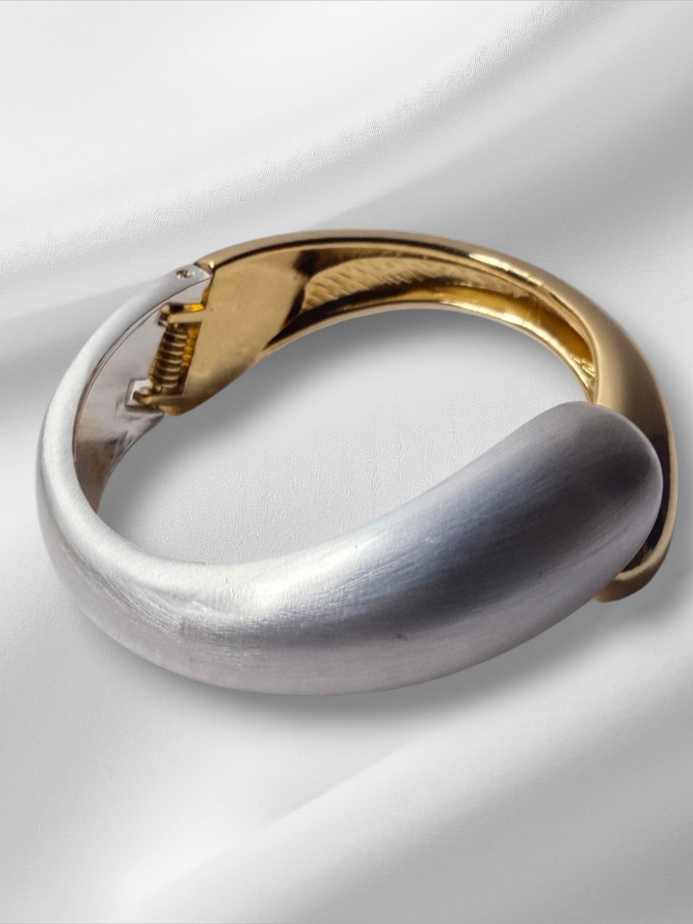 Elegant silver and gold bracelet on white satin background. Lavish Jewellery