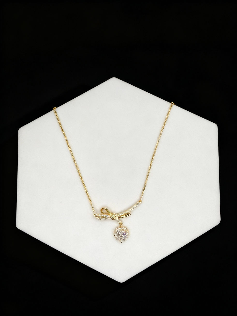 Golden necklace with a bow and diamond pendant Lavish Jewellery on display.