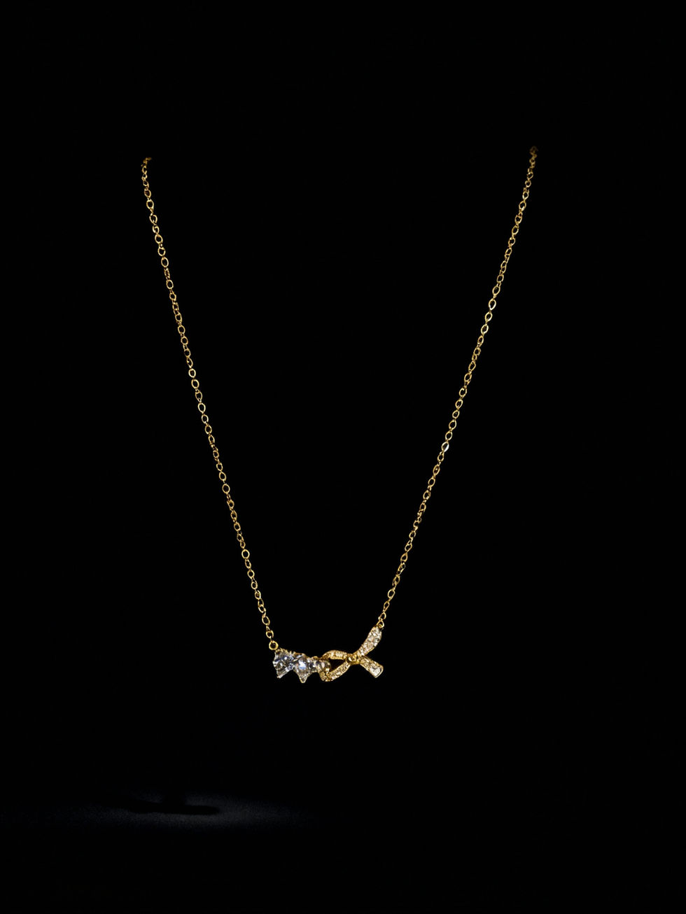 Gold necklace with bow pendant, delicate design on a black background. Lavish Jewellery