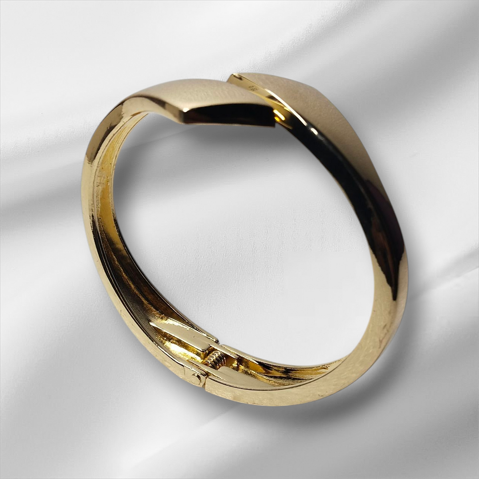 Golden bangle bracelet on white surface; a lavish piece of jewelry