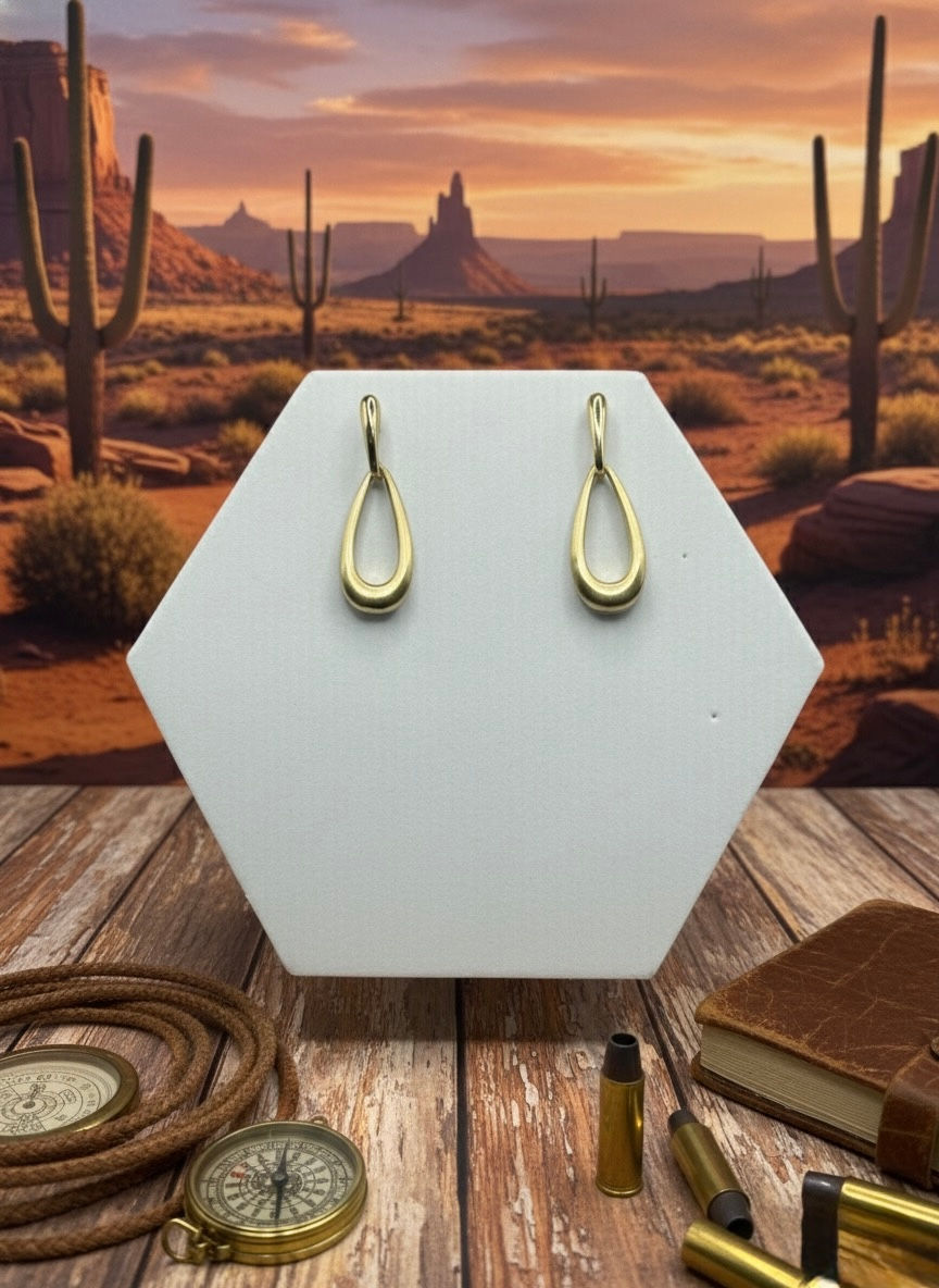 Gold teardrop earrings on display stand, desert background. Lavish Jewellery.