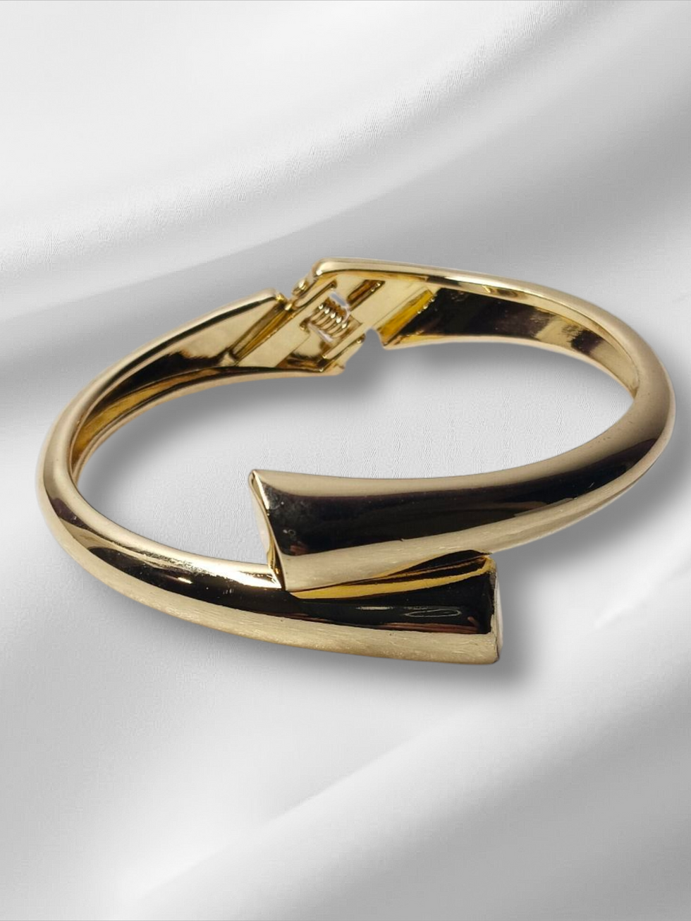 Elegant gold bracelet on white satin background. Lavish Jewellery piece.