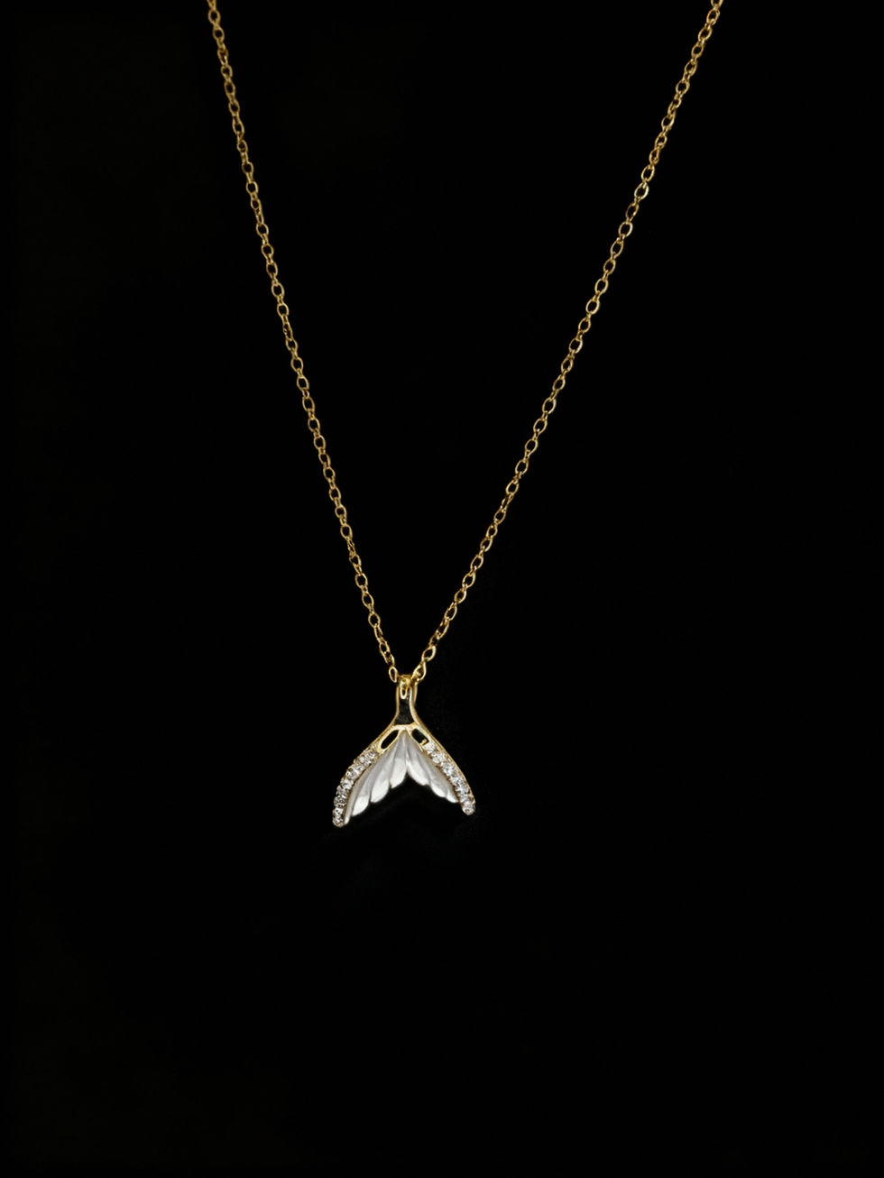 Gold chain necklace with a leaf pendant on a black background. Lavish Jewellery