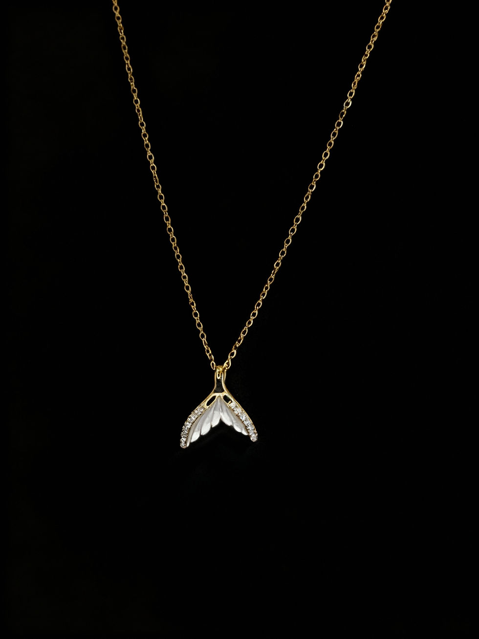 Gold chain necklace with a leaf pendant on a black background. Lavish Jewellery