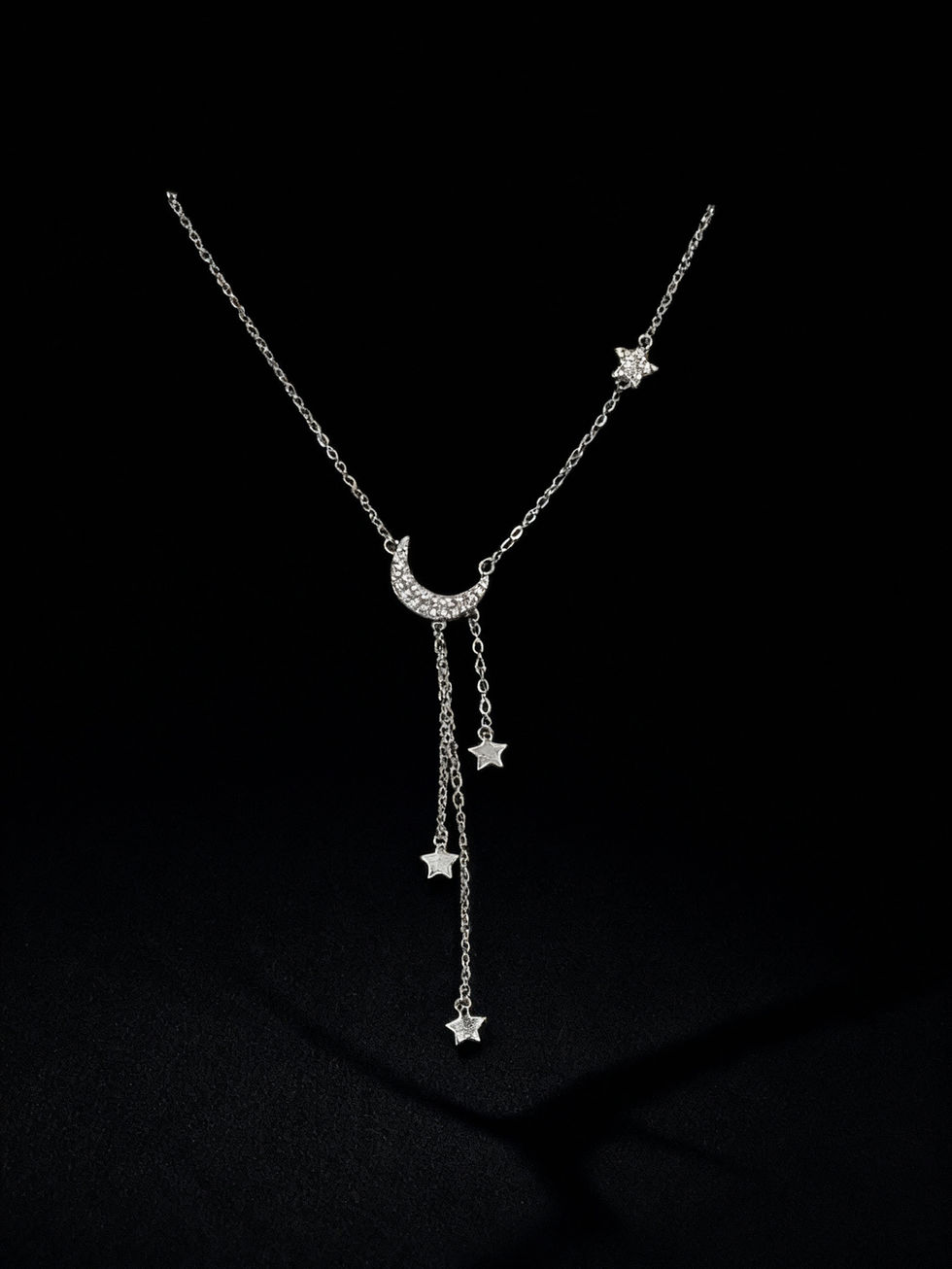 Silver moon and stars necklace with a dark background. Lavish Jewellery.