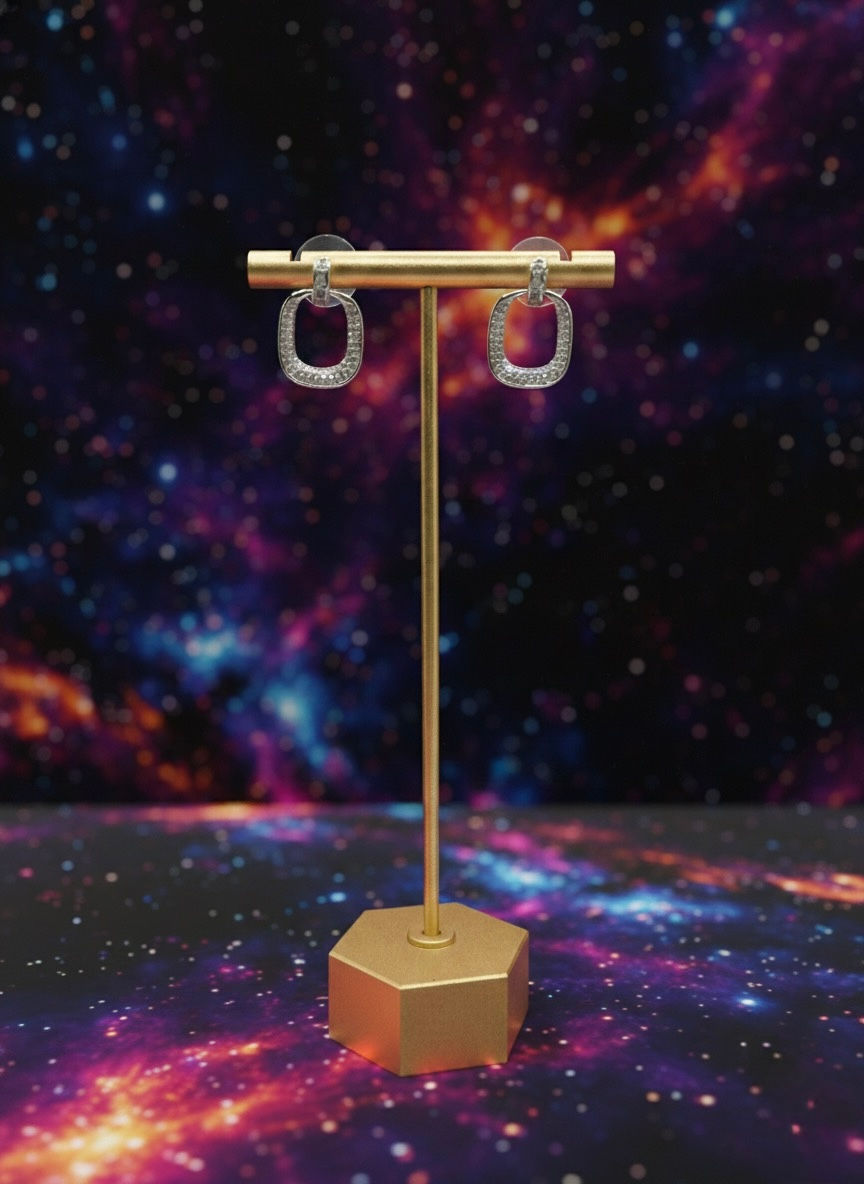 Clear square earrings displayed on a gold stand against a galaxy background. Lavish Jewellery