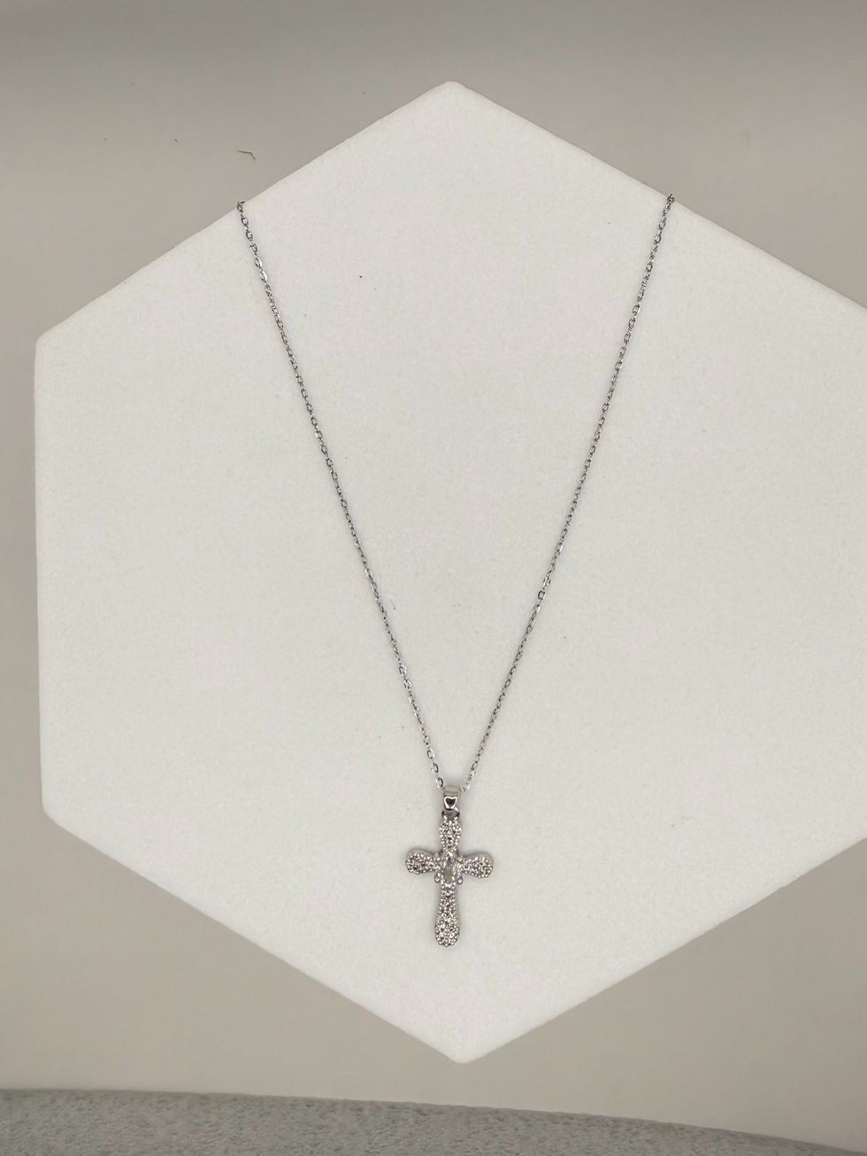 Silver cross necklace pendant on white stand. Lavish Jewellery elegant design.