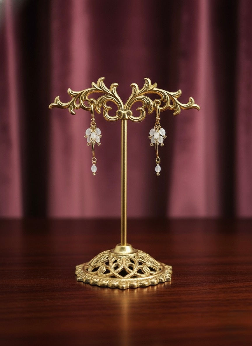 Golden earrings displayed on a stand, intricate design, Lavish Jewellery.
