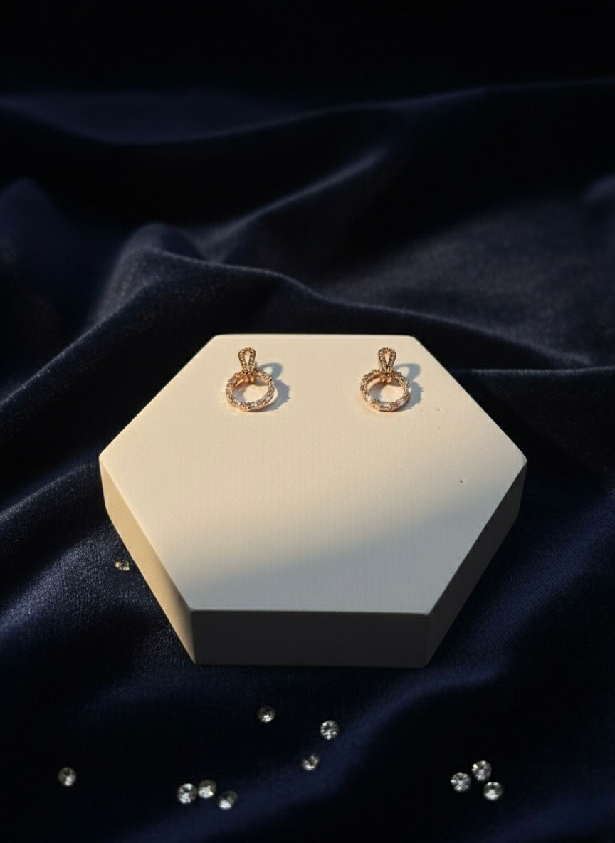 Elegant earrings on display, Small Bow Earring, displayed on a hexagonal stand.