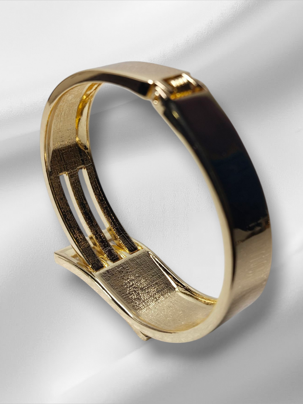 Gold bracelet on white silky cloth. Lavish Jewellery. Beautiful fashion accessory.