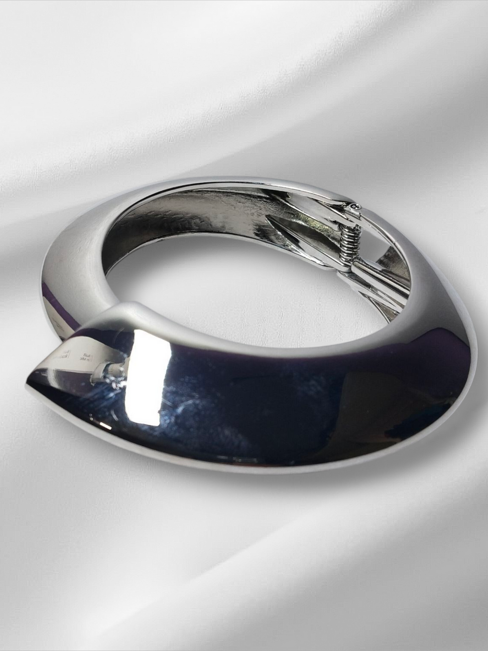 Silver bracelet on white fabric. Smooth, elegant design. Lavish Jewellery.