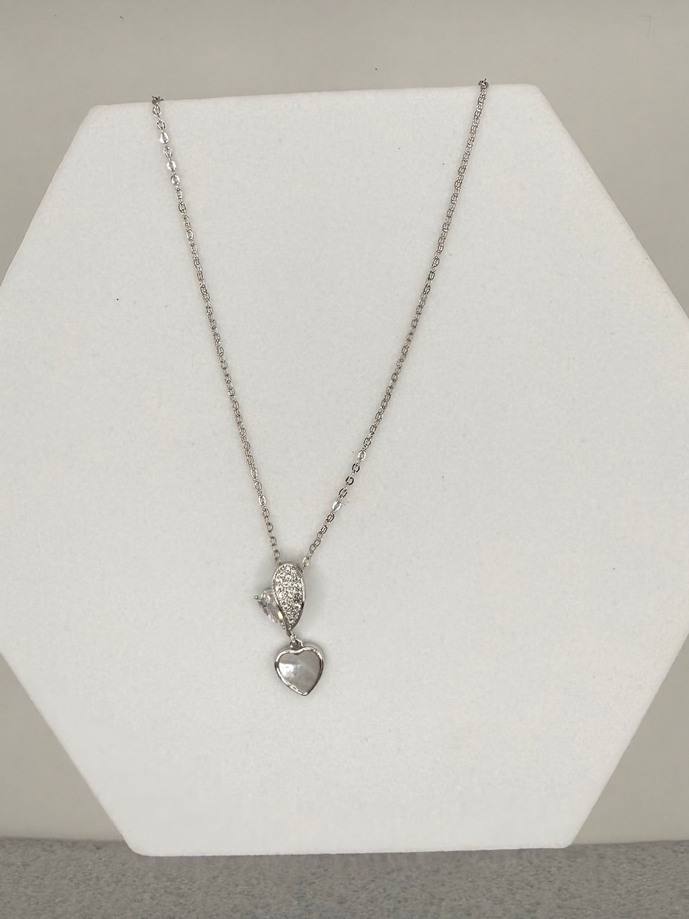 Silver necklace with pearl ribbon pendant on white display Lavish Jewellery.