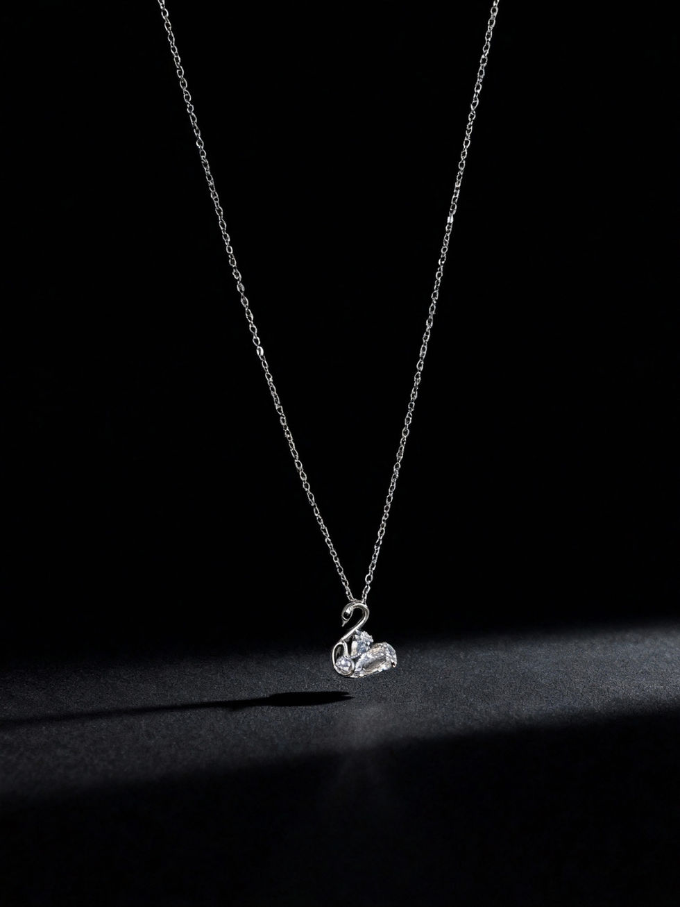 Swan pendant necklace sparkling on a dark background. Lavish Jewellery.