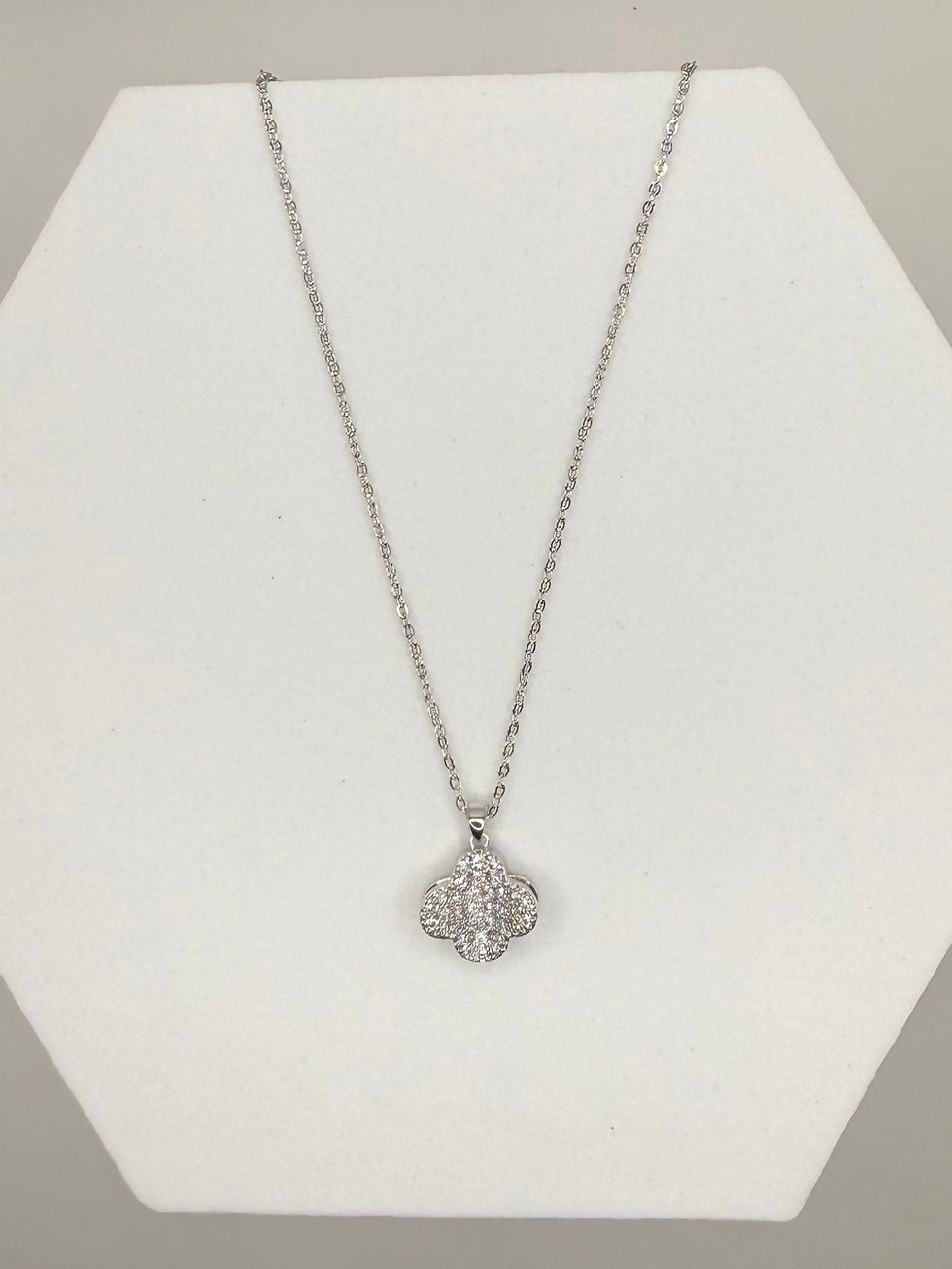 Silver necklace with a pendant displayed on white stand. Pearl Ribbon Pendant Necklace.