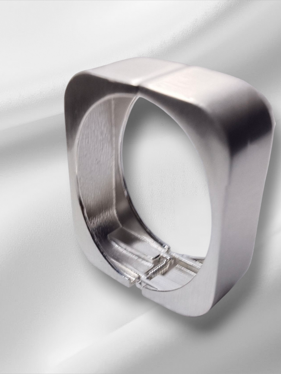Silver square ring against white satin background, Lavish Jewellery.