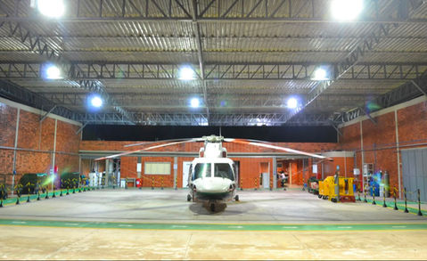 Helicóptero branco estacionado dentro de um hangar iluminado.