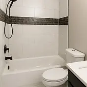 Modern bathroom with white tiled shower, black fixtures, and toilet.