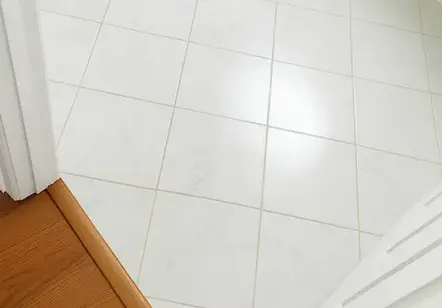 "Professional floor tile installation showing a clean transition between white bathroom tile and wood flooring." in Snellville, GA.