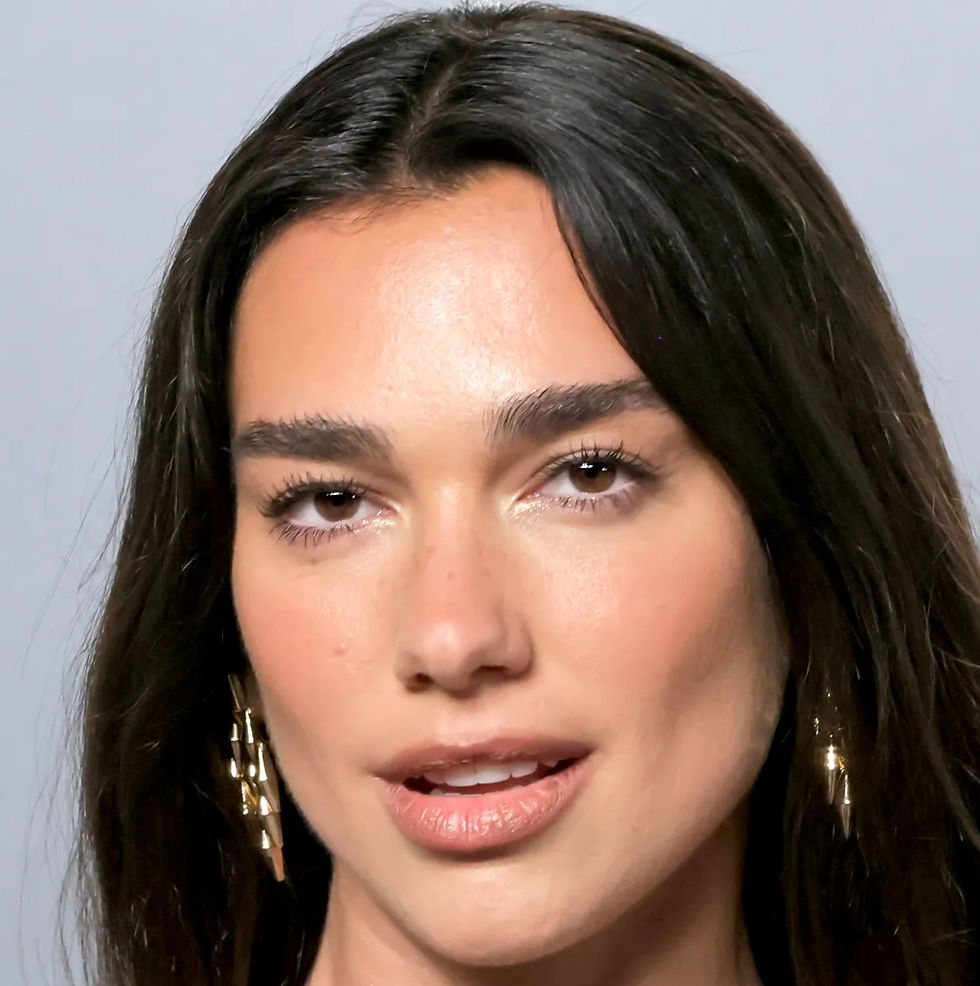 Dua Lipa in a black strapless top, wearing a gold and black jeweled statement necklace with matching drop earrings, hair worn straight and down