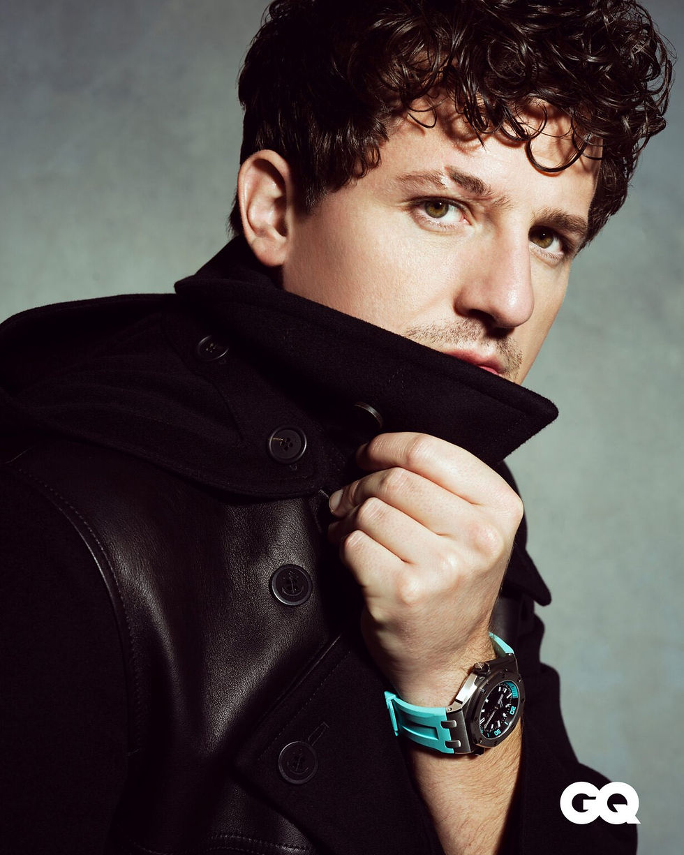 Charlie Puth pulls up the collar of a black leather-and-wool coat, wearing a teal-strapped dive watch, for GQ's cover shoot.
