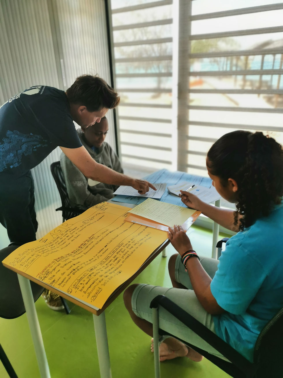 Coach Mathieu Fleury helps students Zya Ngaiohni and Thèmis Tiaiba work on their presentations during a Master Ocean Youth 30x30 workshop. © Pew Bertarelli Ocean Legacy