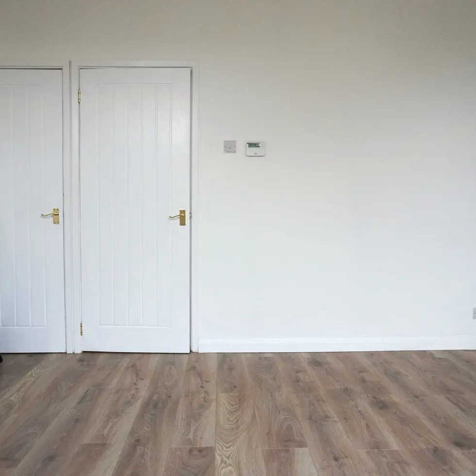 Refurbished living room with white walls, a decorative white fireplace, light wood flooring,
designed by Miriam Roberts.