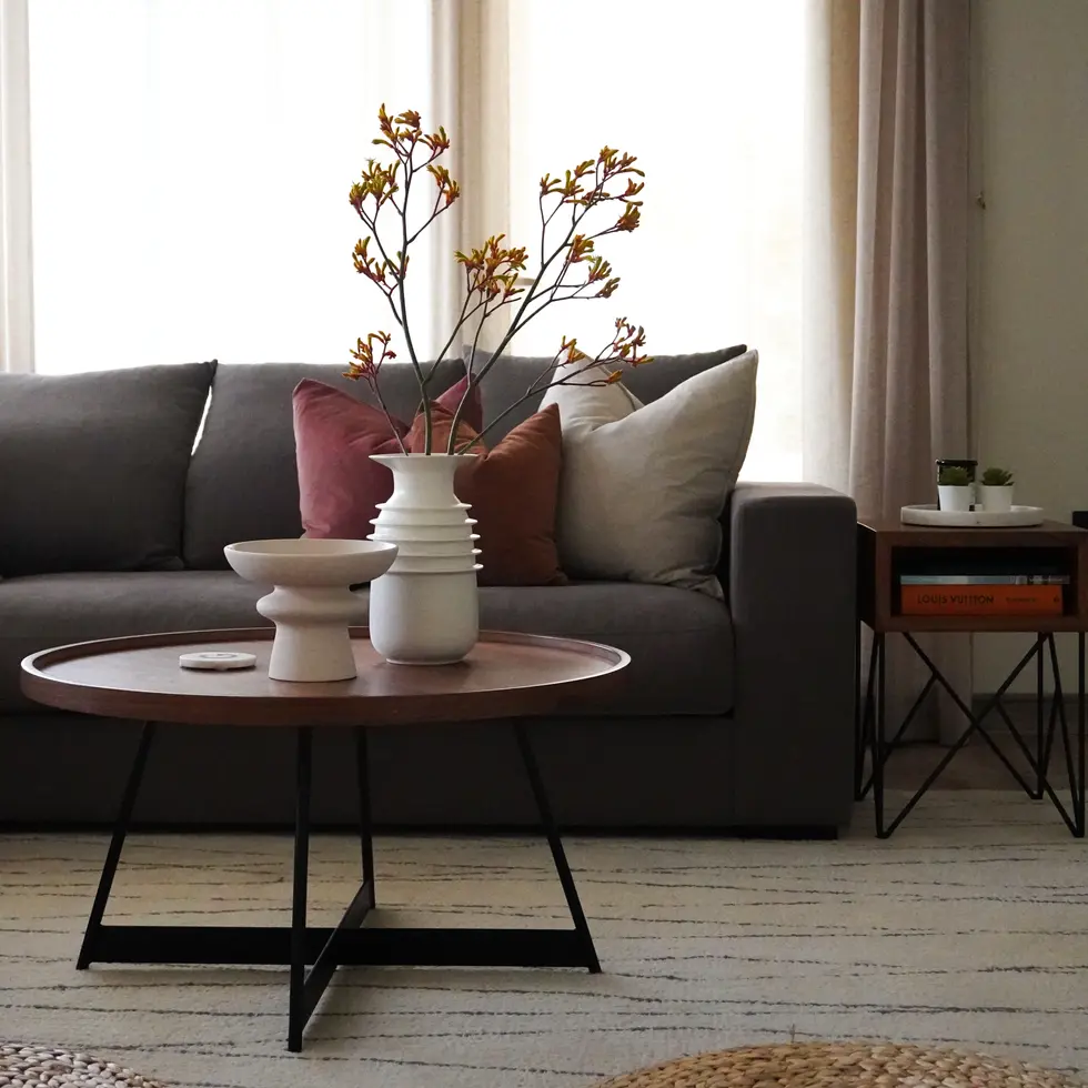 Elegant living room with grey sofa, earthy-toned cushions, and minimalist decor, designed by Miriam Roberts for Roberts Renovations.