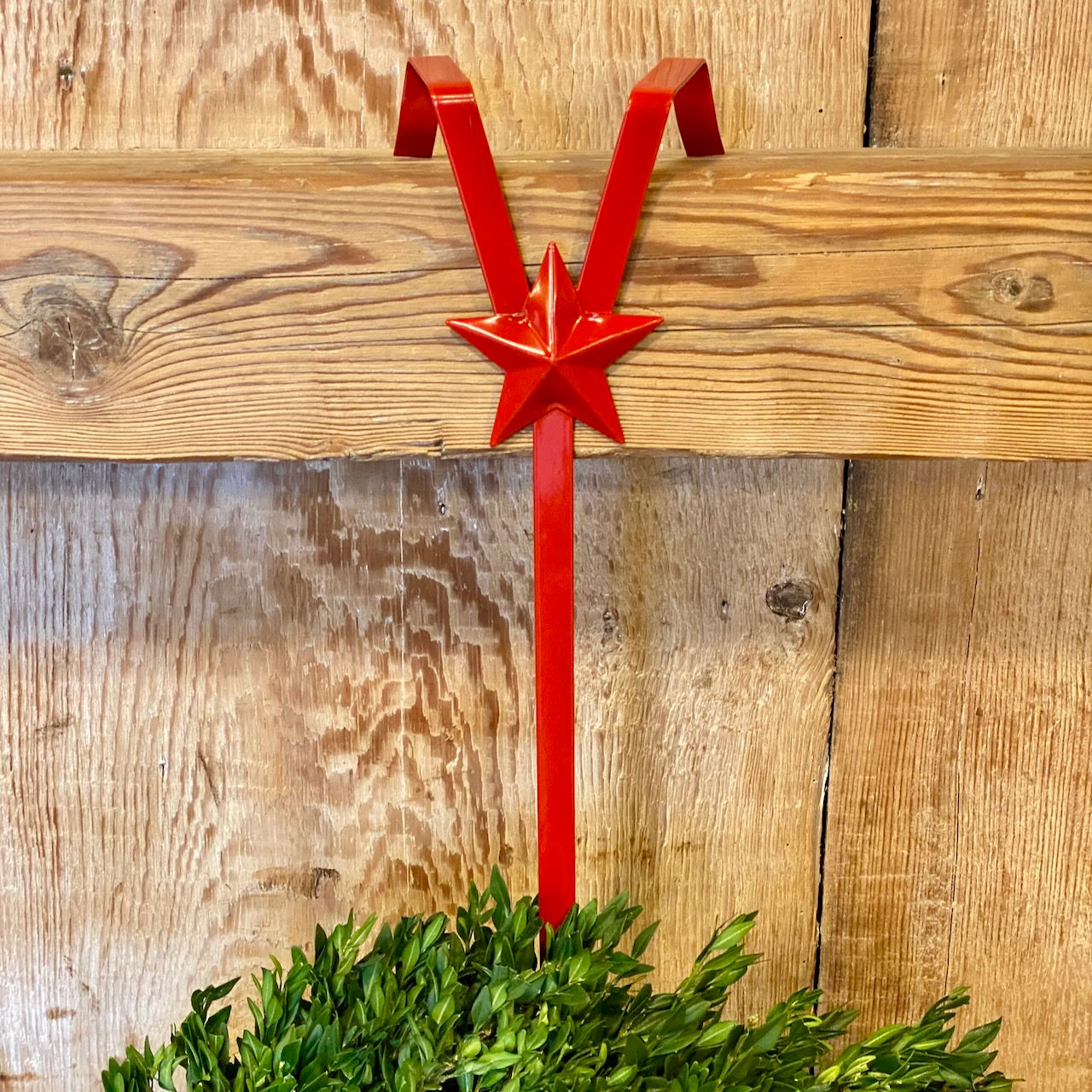 Red star wreath hanger holding a boxwood wreath