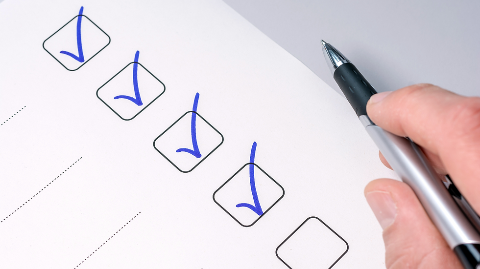 Hand holding pen marks blue checkmarks in boxes on a white checklist paper. Close-up, focused, organized mood.