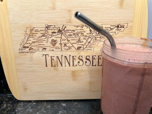 A smoothie in front of a wooden cutting board engraved with a map of Tennessee