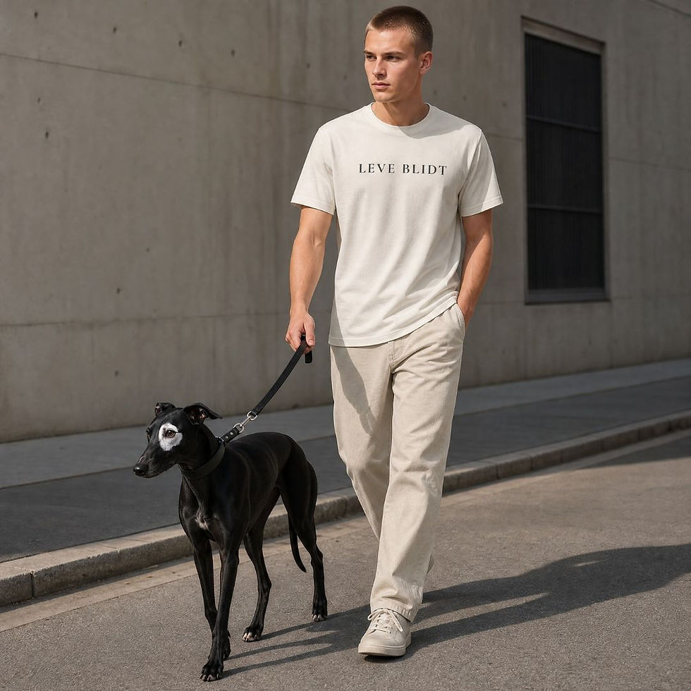 man wearing vintage white LEVE BLIDT tshirt with cream pants walking a black greyhound minimal urban setting