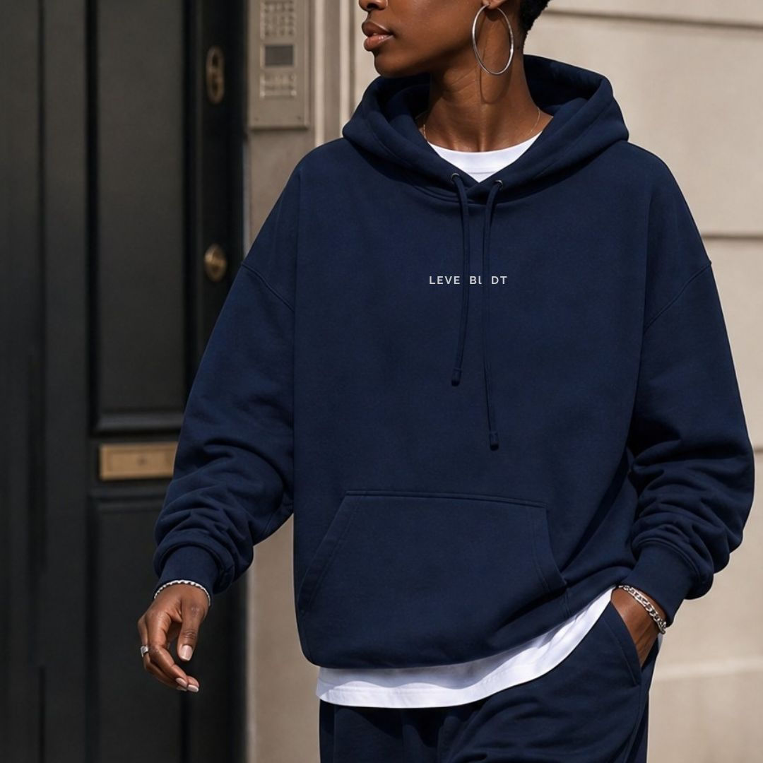 Woman wearing the navy LEVE BLIDT statement hoodie layered over a white tee, styled with silver jewelry