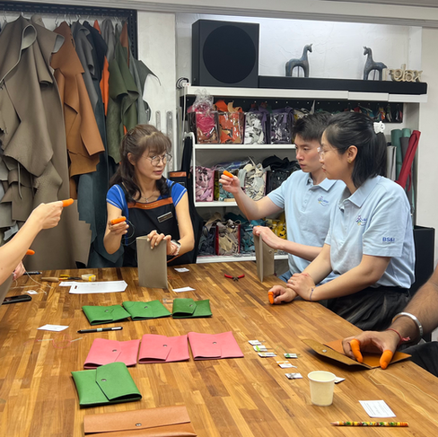 4 people of varying ethnicity are learning to hand-stitch leather together