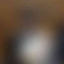 man is smiling while stitching a leather name tag