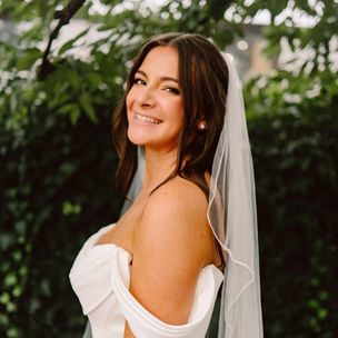 “Sun‑kissed brunette bride with long flowing waves and soft glam makeup, showcasing her fit tan complexion by Nordlie Beauty mobile makeup artist.”