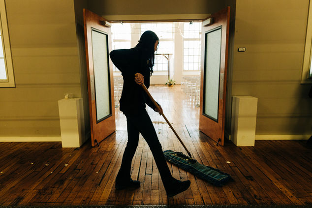 Staff sweeping up flower petals after the ceremony has concluded. 