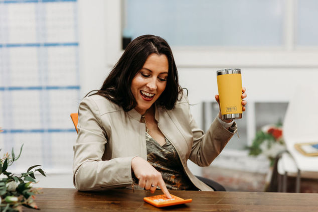 Erin holding her favorite coffee cup while mathing with an orange calculator