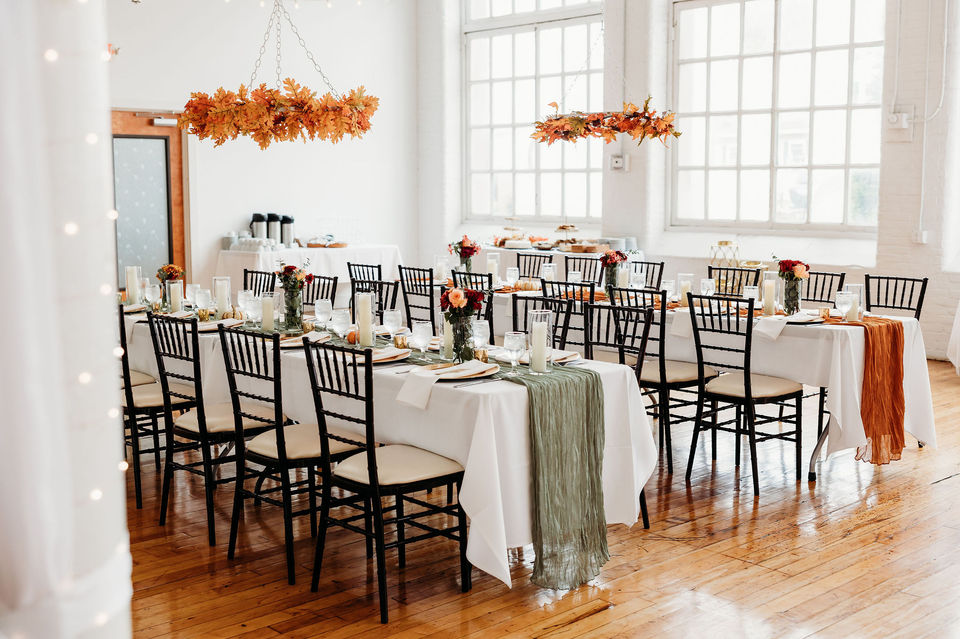 long tables set up with a green runner. Hanging foliage from the ceiling.