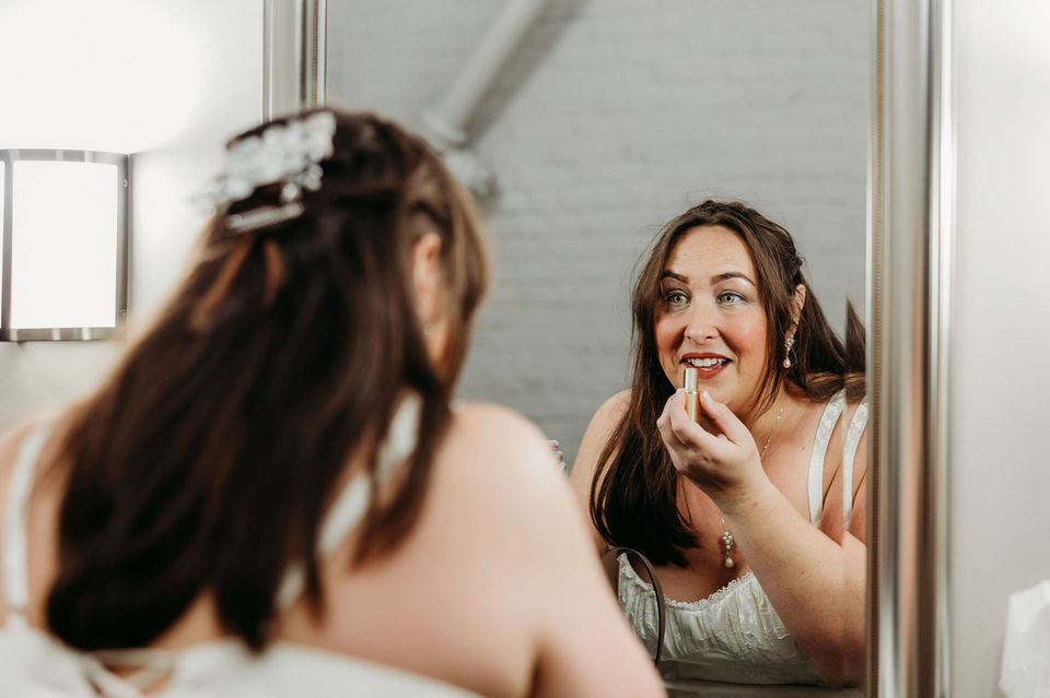 Bride touches up her lipstick in the large wedding suite.