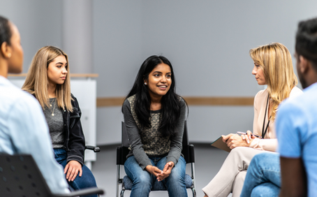 A photo of a teenage girl talking in a circle of other young people