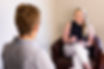 A therapist sits smiling across from a patient during a therapy session
