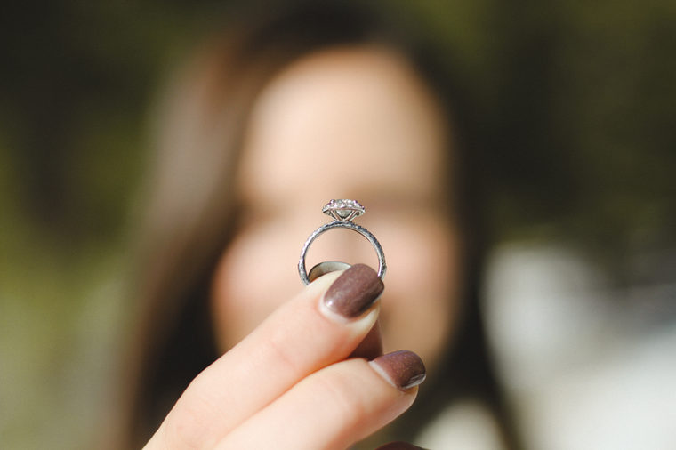Engagement ring held by woman.