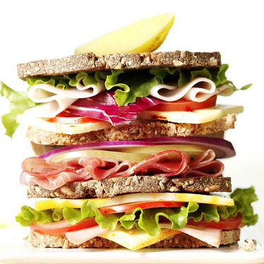Triple-layer sandwich filled with turkey, ham, cheese, lettuce, and onions