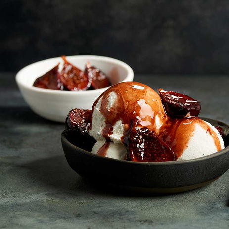Vanilla ice cream scoops topped with caramelized fruit and sauce in a black bow